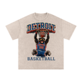 Beige t-shirt with a graphic of a bear playing basketball and 'Detroit Basketball' text on a white background. Detroit Pistons Gear.
